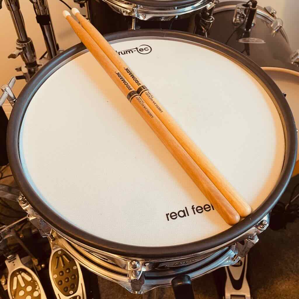 A pair of Pro Mark TX5BN nylon-tipped drumsticks resting on an electronic drum pad