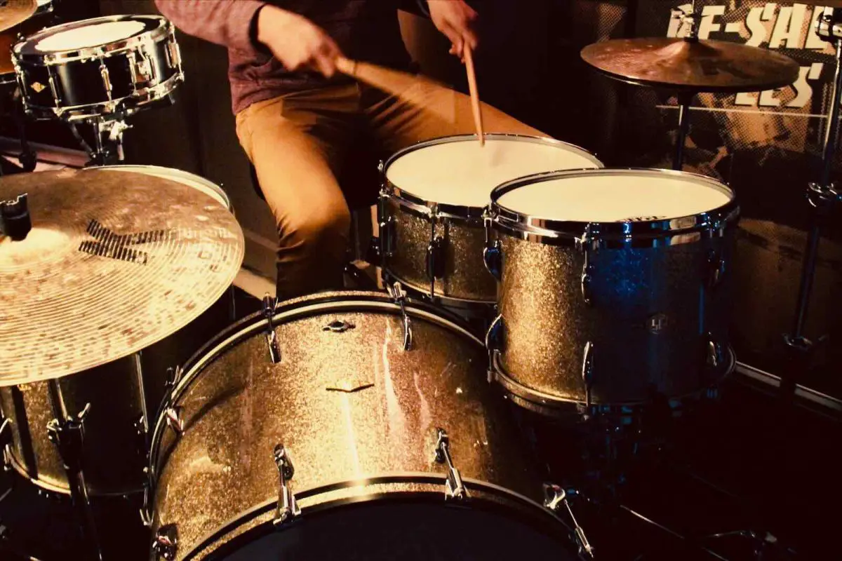 A drummer playing the snare on a gold ASBA drum kit with Zildjian K cymbals